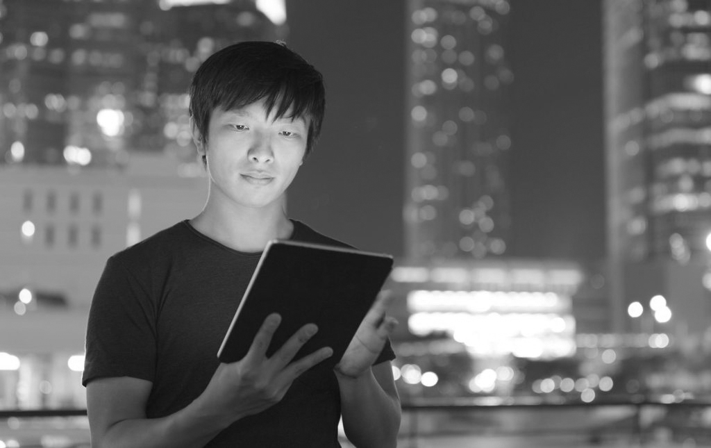 Emerging World of Work Podcast - Asian person looking at a tablet with city skyline behind