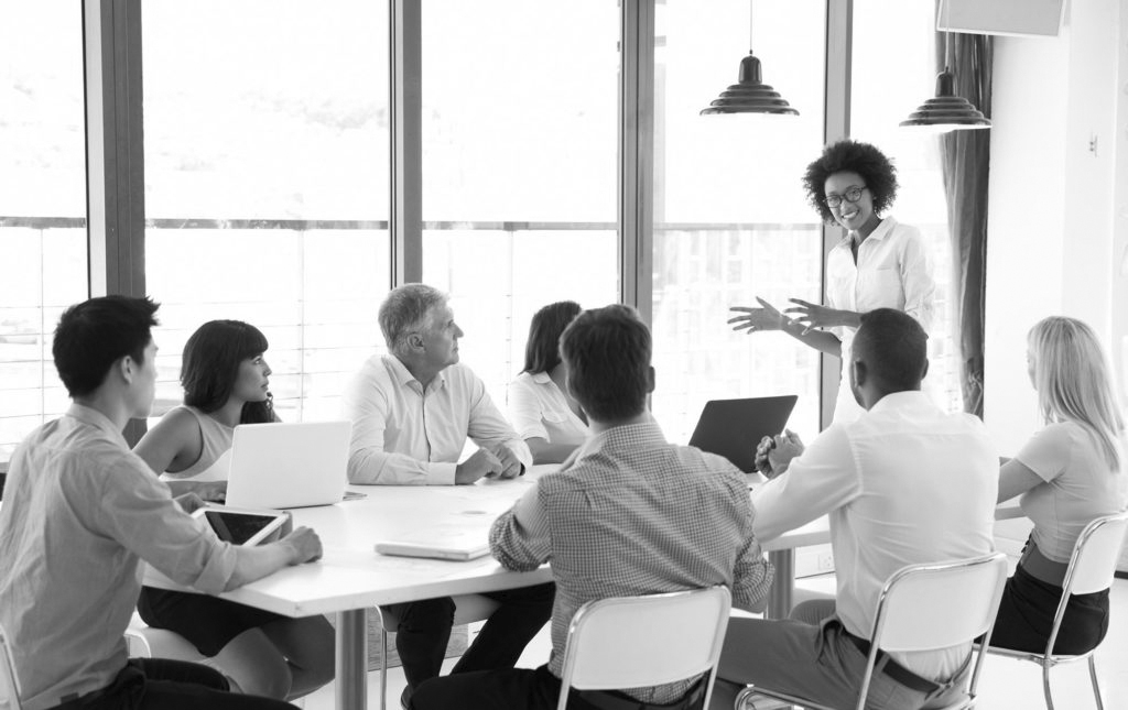 What makes a great leader? Team in a meeting room with a person leading the conversation
